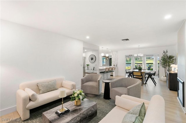 living area featuring light wood finished floors, baseboards, visible vents, and recessed lighting