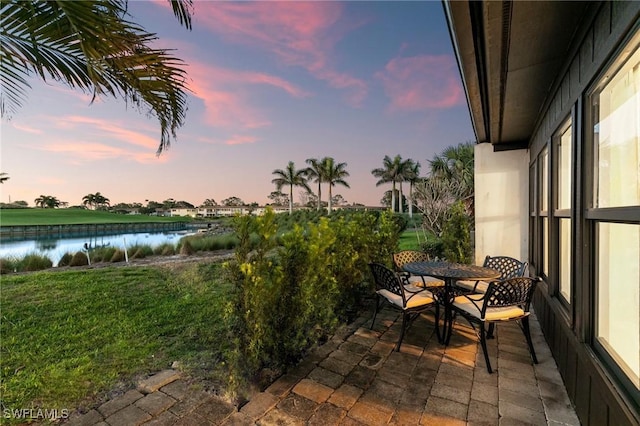 exterior space with outdoor dining space, a water view, and a lawn