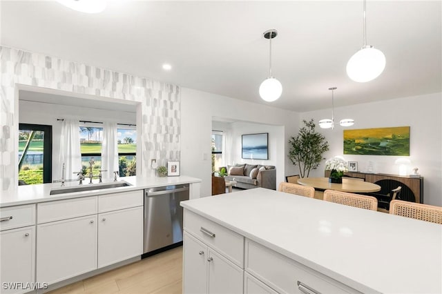 kitchen featuring dishwasher, light countertops, open floor plan, and a sink