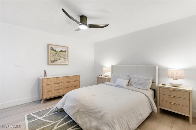 bedroom featuring ceiling fan, light wood-style flooring, and baseboards