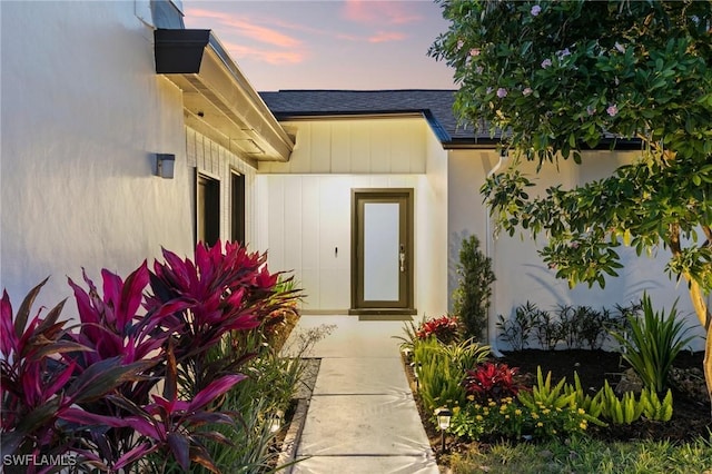 exterior entry at dusk featuring a shingled roof