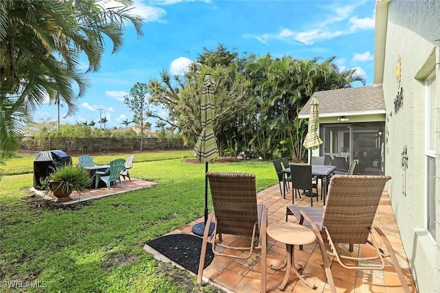 view of yard featuring a sunroom, a fenced backyard, a patio, and outdoor dining area