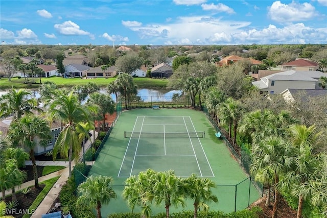 view of tennis court featuring a residential view, a water view, and fence