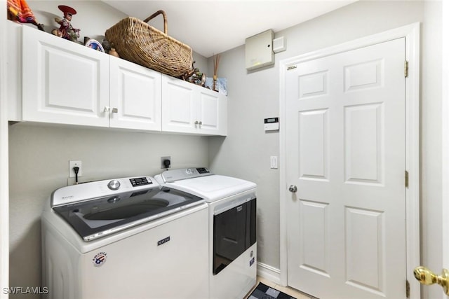 washroom with cabinet space, baseboards, and washing machine and clothes dryer