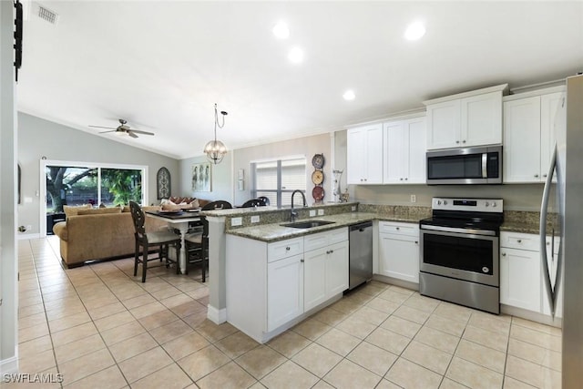 kitchen featuring light tile patterned floors, appliances with stainless steel finishes, open floor plan, a sink, and a peninsula