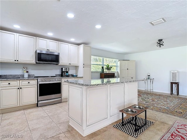 4364 Beechwood Lake Dr, Naples, FL 34112 - kitchen featuring light stone countertops, visible vents, appliances with stainless steel finishes, and a center island