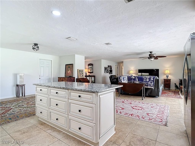 4364 Beechwood Lake Dr, Naples, FL 34112 - kitchen featuring a center island, a ceiling fan, freestanding refrigerator, light tile patterned flooring, and light stone countertops