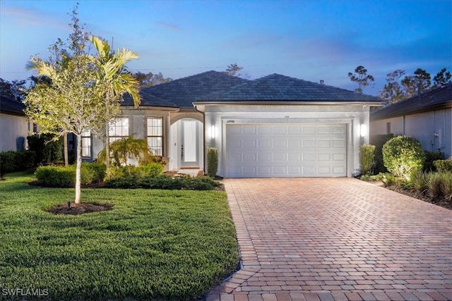 single story home featuring a front lawn, decorative driveway, an attached garage, and stucco siding