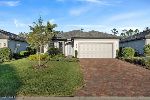 single story home with stucco siding, decorative driveway, a front yard, a shingled roof, and an attached garage