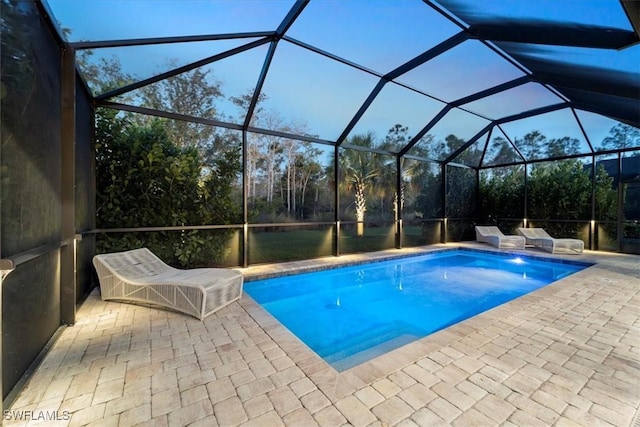 outdoor pool featuring glass enclosure and a patio area