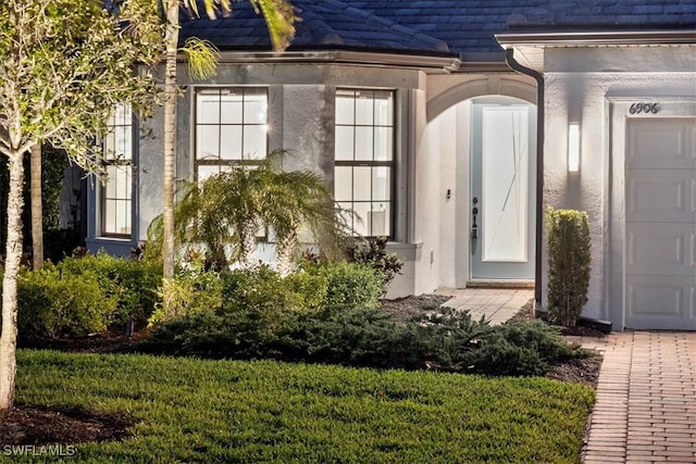 property entrance featuring a tile roof, an attached garage, and stucco siding