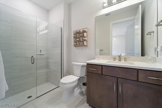 full bathroom with toilet, a stall shower, and vanity