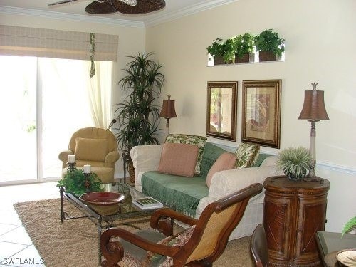 living area with tile patterned flooring, ornamental molding, and a ceiling fan