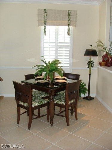 dining room with light tile patterned floors, ornamental molding, and baseboards