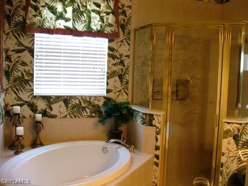 full bathroom featuring wallpapered walls, a shower stall, and a bath