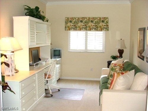 office space featuring baseboards, ornamental molding, built in study area, and light colored carpet