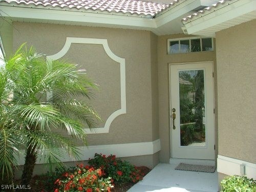 entrance to property featuring a tile roof and stucco siding