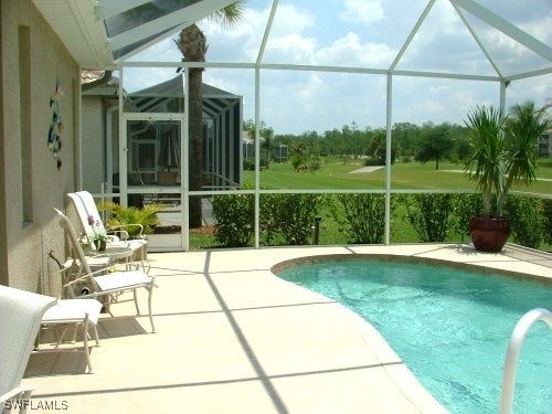 outdoor pool with a patio area and glass enclosure