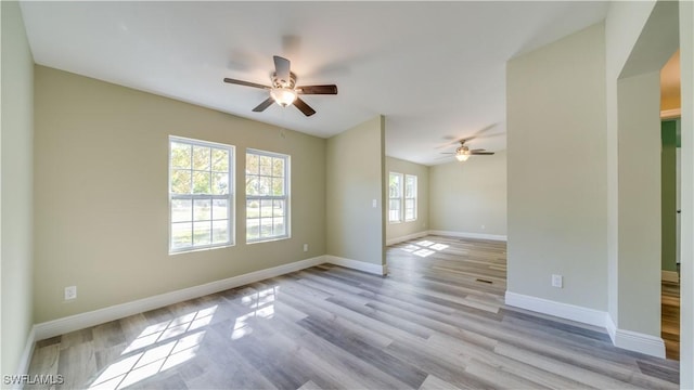 empty room with wood finished floors, a ceiling fan, and baseboards