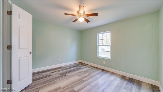 empty room featuring ceiling fan, baseboards, and wood finished floors