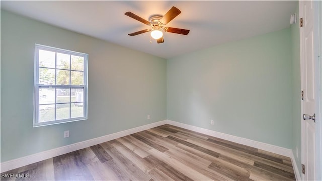 empty room with wood finished floors, a ceiling fan, and baseboards