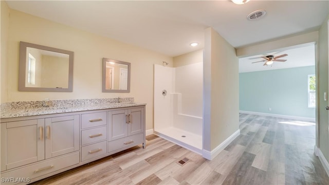 bathroom featuring visible vents, walk in shower, a sink, and wood finished floors