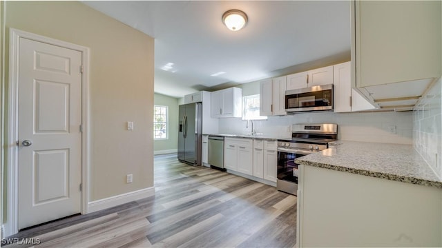 kitchen with white cabinetry, appliances with stainless steel finishes, backsplash, and a sink