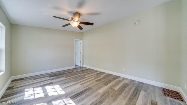 unfurnished room featuring visible vents, ceiling fan, baseboards, and wood finished floors