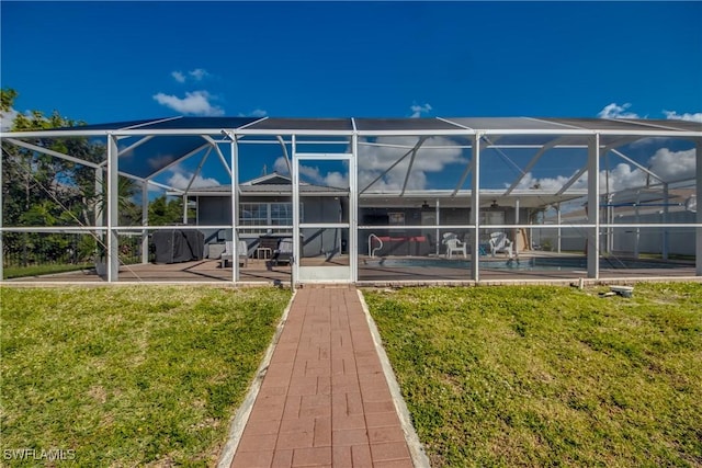 rear view of house featuring glass enclosure, an outdoor pool, a lawn, and a patio