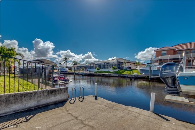 view of dock with a water view, fence, and a residential view