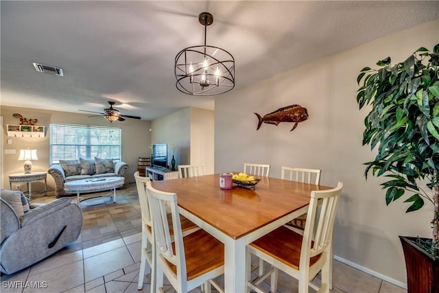 dining room with ceiling fan with notable chandelier, visible vents, baseboards, and light tile patterned floors