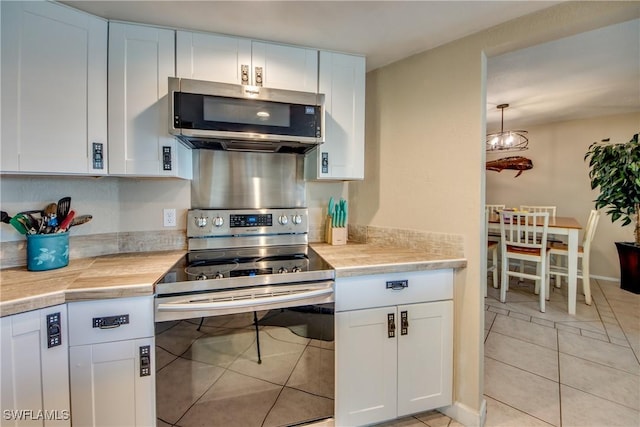 kitchen featuring light tile patterned floors, stainless steel appliances, light countertops, and white cabinetry