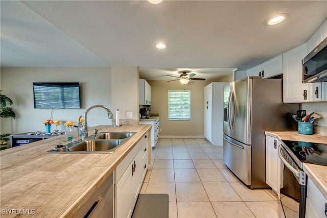 kitchen with light tile patterned floors, stainless steel appliances, light countertops, white cabinetry, and a sink