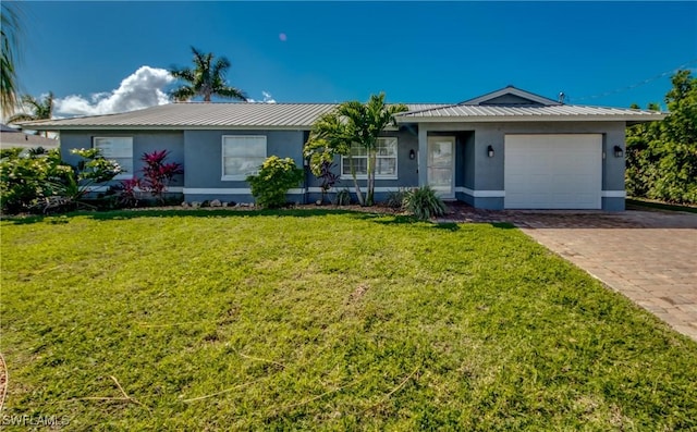 ranch-style home featuring metal roof, an attached garage, decorative driveway, stucco siding, and a front lawn