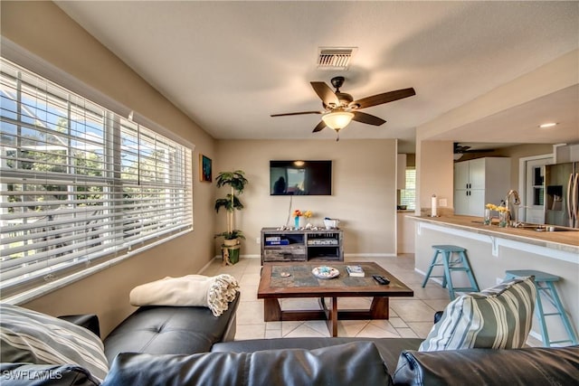 living area with plenty of natural light, light tile patterned flooring, visible vents, and baseboards