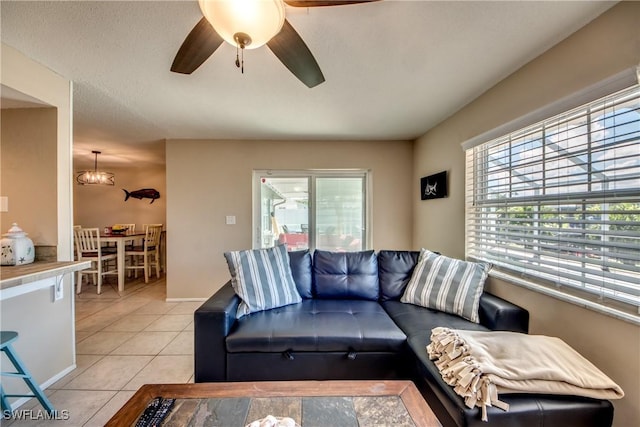 living area with light tile patterned flooring, a ceiling fan, and baseboards