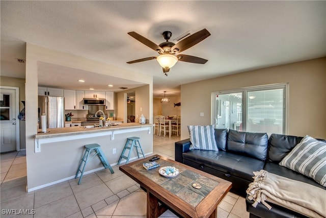 living area with ceiling fan, visible vents, baseboards, and light tile patterned flooring