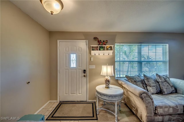 foyer entrance with light tile patterned floors and baseboards