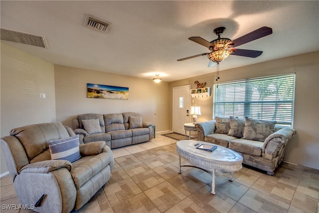 living area with baseboards, visible vents, and a ceiling fan