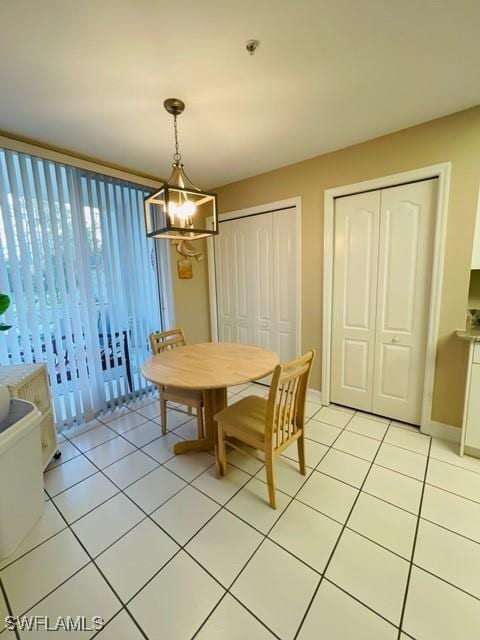 dining area with light tile patterned floors, baseboards, and an inviting chandelier