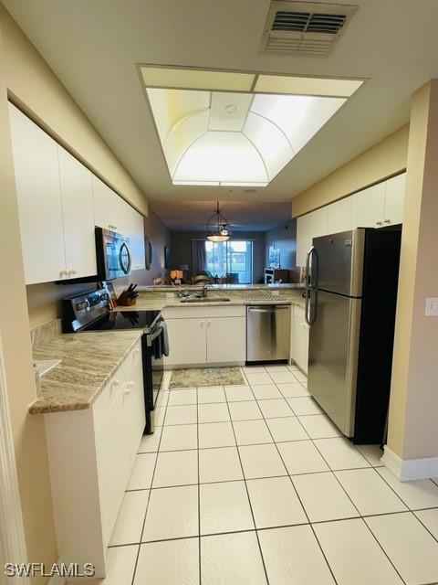 kitchen with appliances with stainless steel finishes, white cabinets, visible vents, and light tile patterned flooring