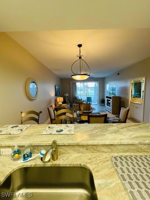 kitchen with vaulted ceiling, hanging light fixtures, open floor plan, and a sink