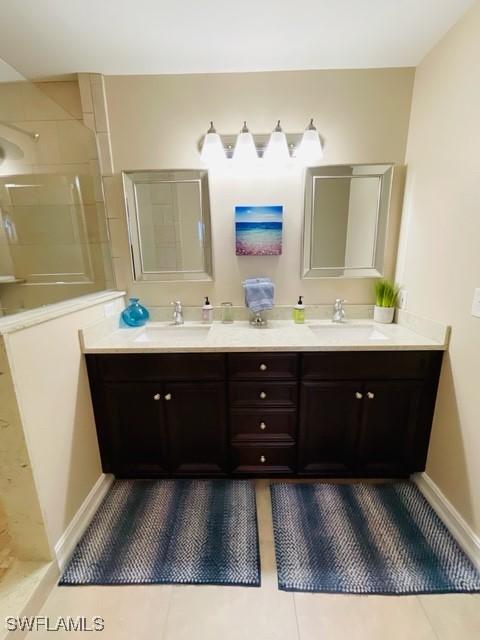 full bathroom with double vanity, a walk in shower, and a sink