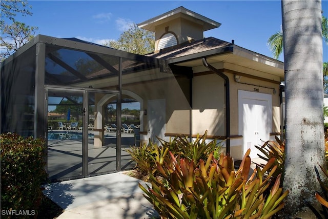 entrance to property with stucco siding, an outdoor pool, and a patio