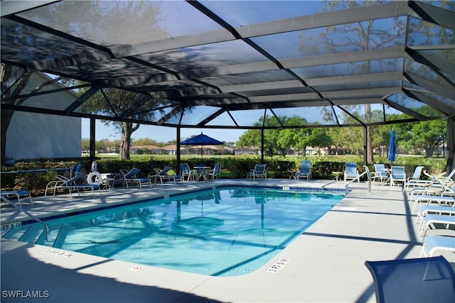 community pool with glass enclosure and a patio area