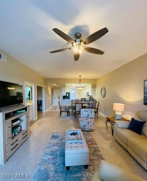 living area with a ceiling fan, visible vents, and baseboards