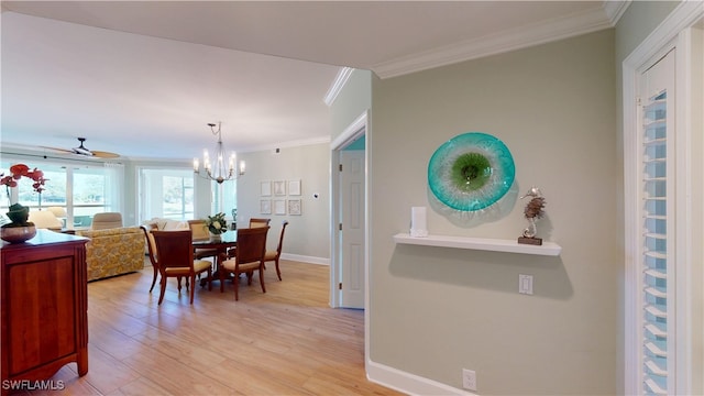 dining space with ceiling fan with notable chandelier, ornamental molding, light wood-style flooring, and baseboards