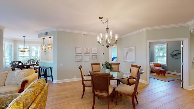 dining space featuring light wood finished floors, baseboards, ornamental molding, and a notable chandelier