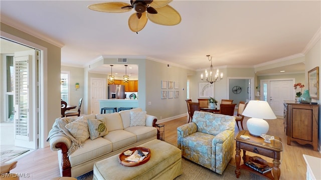 living room featuring ornamental molding, light wood finished floors, ceiling fan with notable chandelier, and visible vents