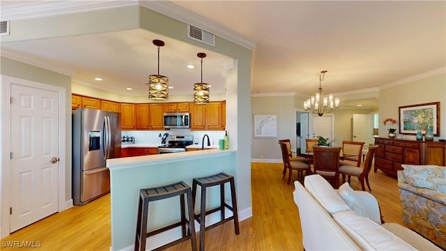 kitchen featuring visible vents, brown cabinetry, appliances with stainless steel finishes, open floor plan, and light wood-style floors